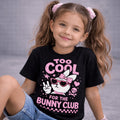 Too cool for the bunny club Easter T-Shirt Pink worn by a girl with pigtails and sunglasses, smiling in a playful pose.